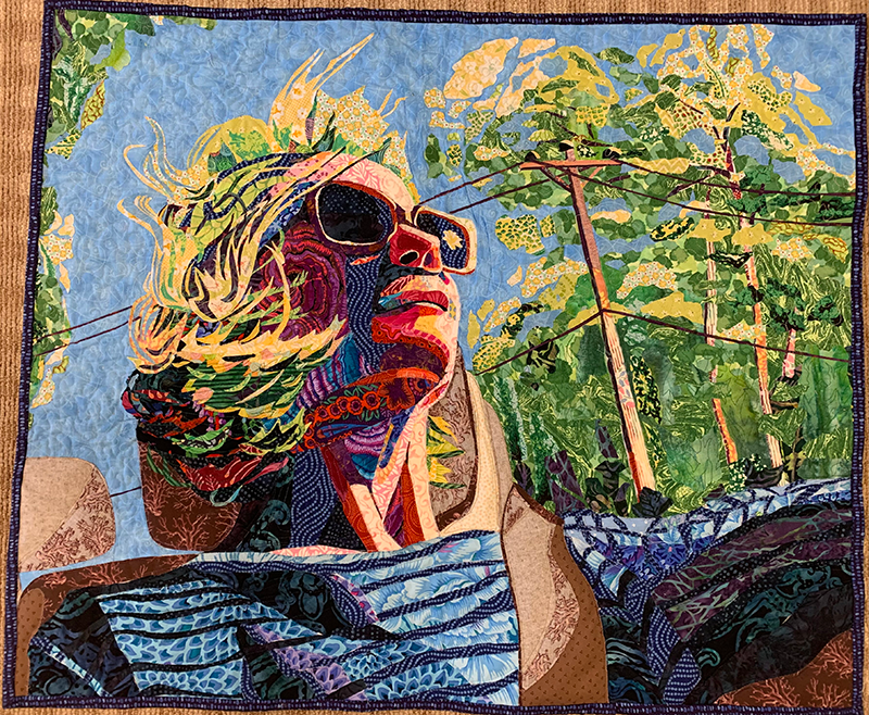 A picture of a quilt of a woman in a convertible