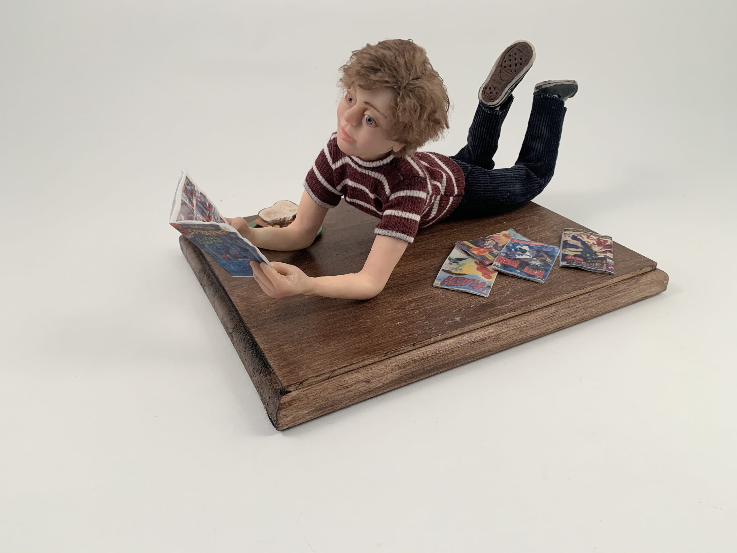 A handmade doll of a boy reading comic books.